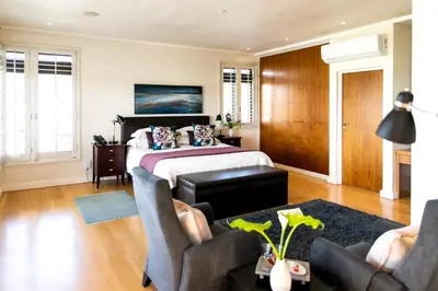 a bedroom with a bed and two chairs at Selkirk House in Hermanus