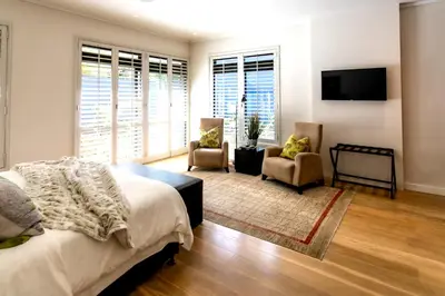 a bedroom with a bed and two chairs and a television at Selkirk House in Hermanus