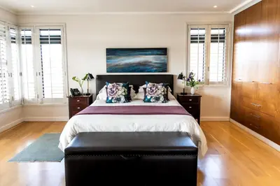 a bedroom with a large bed with a black ottoman at Selkirk House in Hermanus