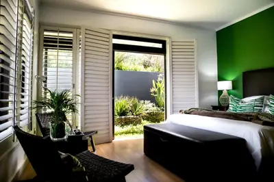 a bedroom with green walls and a bed and a window at Selkirk House in Hermanus