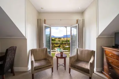 two chairs and a table in a room with a window at Wild Mushroom Country House in Stellenbosch