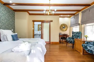 a bedroom with two beds and a desk and a chair at Evergreen Manor and Spa in Stellenbosch