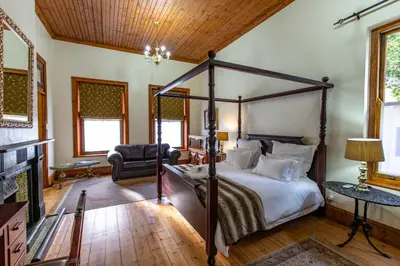 a bedroom with a canopy bed and a fireplace at Evergreen Manor and Spa in Stellenbosch