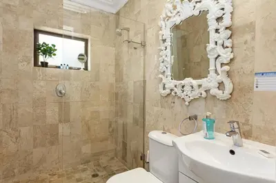 a bathroom with a toilet and a sink and a mirror at OCEAN BREEZE SUNSET BEACH - Cape Town in Cape Town