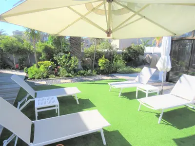 a patio with two chairs and an umbrella at OCEAN BREEZE SUNSET BEACH - Cape Town in Cape Town