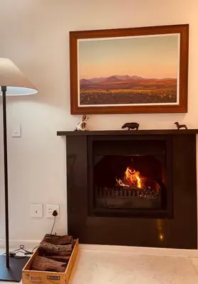 a living room with a fireplace with a painting above it at Le Grenier Luxury Loft in Franschhoek