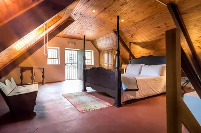 a bedroom with a bed and a wooden ceiling at De Leeuwenhof Estate in Paarl