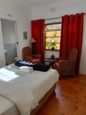 a bedroom with a bed and two chairs and a window at John Bauer Pottery Studio in Cape Town