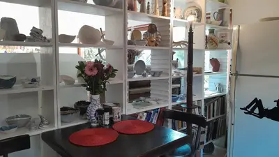 a room with a table with red plates and a refrigerator at John Bauer Pottery Studio in Cape Town