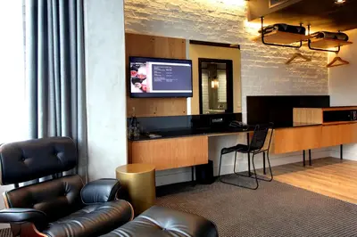 a room with a desk with a television and a couch at Century City Hotel Urban Square in Cape Town