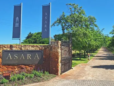 a sign on a brick wall next to a fence at ASARA Wine Estate & Hotel in Stellenbosch