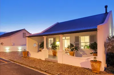 a white house with potted plants in a driveway at The Vishuis in Hermanus