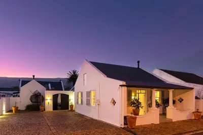 a white house with a black roof at dusk at The Vishuis in Hermanus