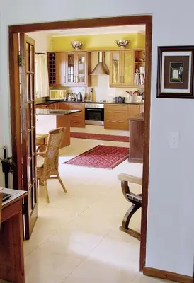 a kitchen with wooden cabinets and a table and chairs at Golf and Garden Guesthouse in Somerset West
