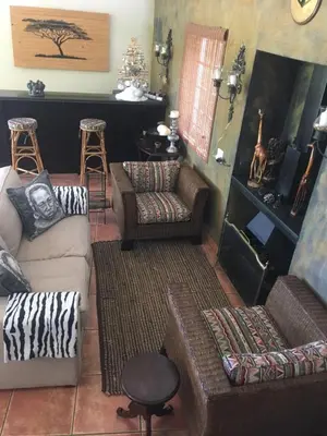 a living room with couches and chairs and a fireplace at Golf and Garden Guesthouse in Somerset West