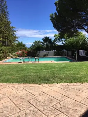 a swimming pool with a picnic table in a yard at Golf and Garden Guesthouse in Somerset West