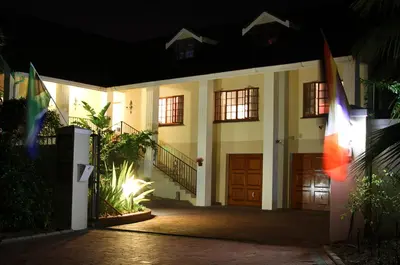 a building at night with flags in front of it at Golf and Garden Guesthouse in Somerset West