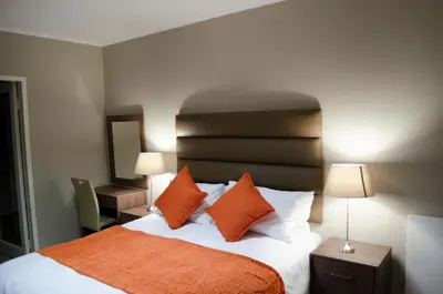 a bedroom with a bed with orange and white pillows at Mayfair Luxury Apartments in Cape Town