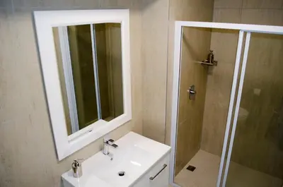 a bathroom with a sink and a shower with a mirror at Mayfair Luxury Apartments in Cape Town