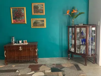 a blue wall with a cabinet and a table with a vase at The Little Hideaway Guesthouse in Stellenbosch