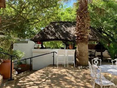 a patio with a table and chairs under a tree at The Little Hideaway Guesthouse in Stellenbosch