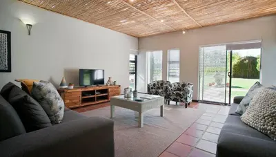 a living room with a couch and a tv and a table at Rest at Chabivin in Stellenbosch