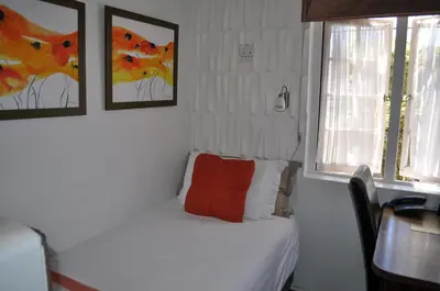 a bedroom with a bed with a red pillow on it at Cotswold House in Cape Town