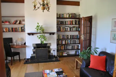 a living room with a fireplace and book shelves at Cotswold House in Cape Town