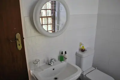 a bathroom with a sink and a toilet and a mirror at Cotswold House in Cape Town