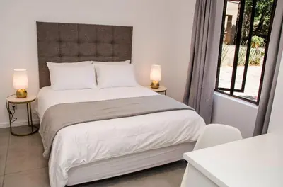 a bedroom with a white bed with two lamps on tables at Lavinia Lifestyle in Stellenbosch