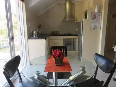 a kitchen with a glass table with a vase of flowers on it at Milas Place in Somerset West