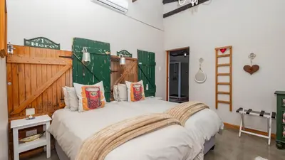 a bedroom with a large white bed with pillows at Seven Oaks Vineyard Cottages in Wolseley