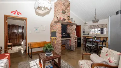 a living room with a brick fireplace and a table at Seven Oaks Vineyard Cottages in Wolseley