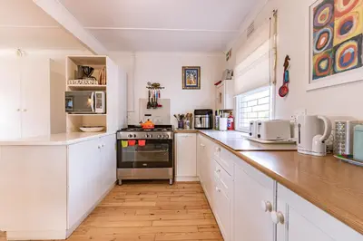 a kitchen with white cabinets and a stove top oven at The Mermaid's Tail in Pringle Bay