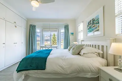 a bedroom with a white bed with blue accents at The Mermaid's Tail in Pringle Bay