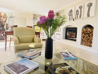 a living room with a glass table with a vase with flowers at Residence Vive la Vie in Franschhoek