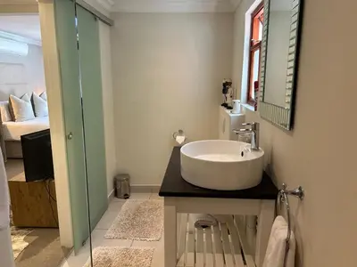 a bathroom with a white sink and a bedroom at Residence Vive la Vie in Franschhoek