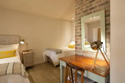 a bedroom with a desk with a mirror and two beds at Viettz Suite in Stellenbosch