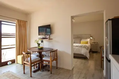 a room with a table and a bedroom with a bed at Viettz Suite in Stellenbosch