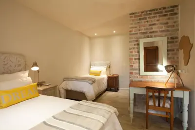 a bedroom with two beds and a brick wall at Viettz Suite in Stellenbosch
