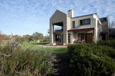a large white house on a field with bushes at Viettz Suite in Stellenbosch