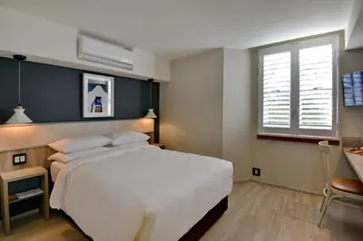 a bedroom with a large white bed and a window at Town Lodge Bellville in Bellville