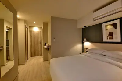 a bedroom with a large white bed and a hallway at Town Lodge Bellville in Bellville