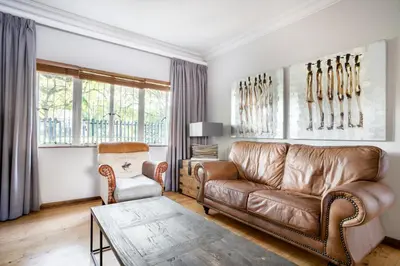 a living room with a leather couch and a chair at Avemore Wag n Bietjie No 1 in Stellenbosch