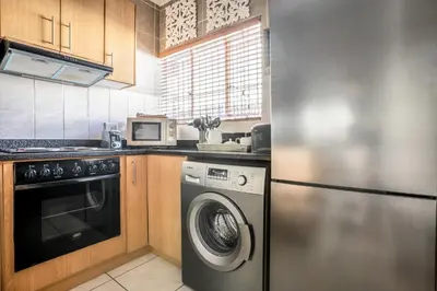a kitchen with a washing machine and a microwave at Avemore Wag n Bietjie No 1 in Stellenbosch