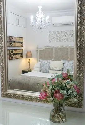 a bedroom with a large mirror and flowers in a vase at Avemore Wag n Bietjie No 1 in Stellenbosch
