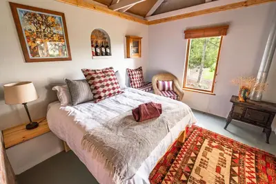 a bedroom with a bed and a table and a window at Belfield Wines and Farm Cottages in Grabouw
