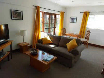 a living room with a couch and a tv at Rose Cottage in Hermanus