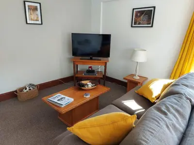 a living room with a couch and a television at Rose Cottage in Hermanus