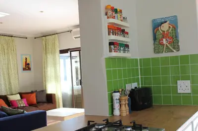 a kitchen with green tile on the walls and a couch at 'Die Braaihuis'- sleeps 6, Large Veranda, Sea Views, Central and Fabulous! in Gordonʼs Bay